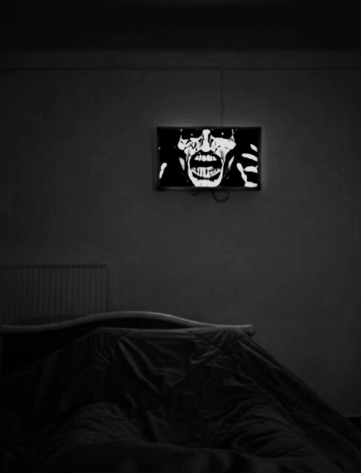 Écran diffusant un visage dans une pièce sombre, réflexion sur l'image et la mémoire